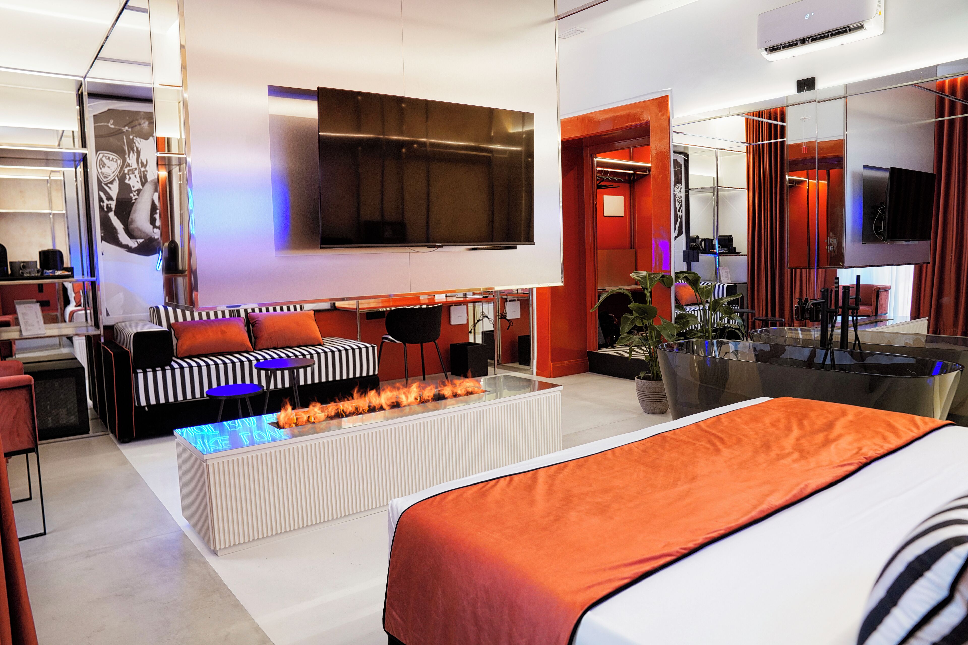 Suite con letto matrimoniale, divano a righe, camino al bioetanolo e vasca freestanding