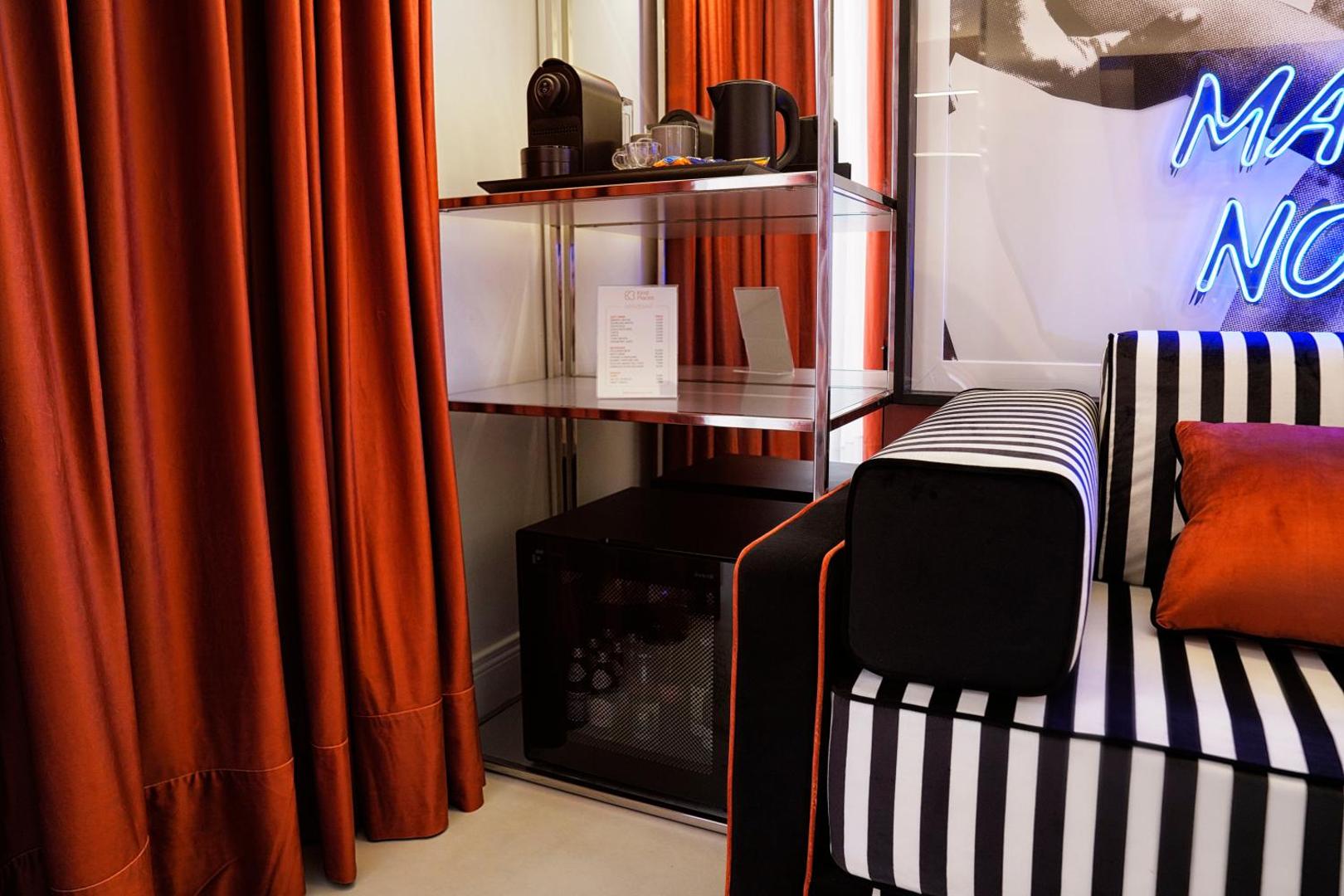 Minibar e ripiani con listino, tende arancio e divano a righe