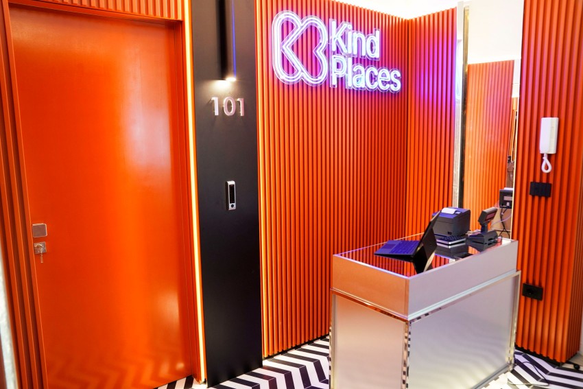 Insegna al neon Kind Places sulla parete di legno arancio della reception