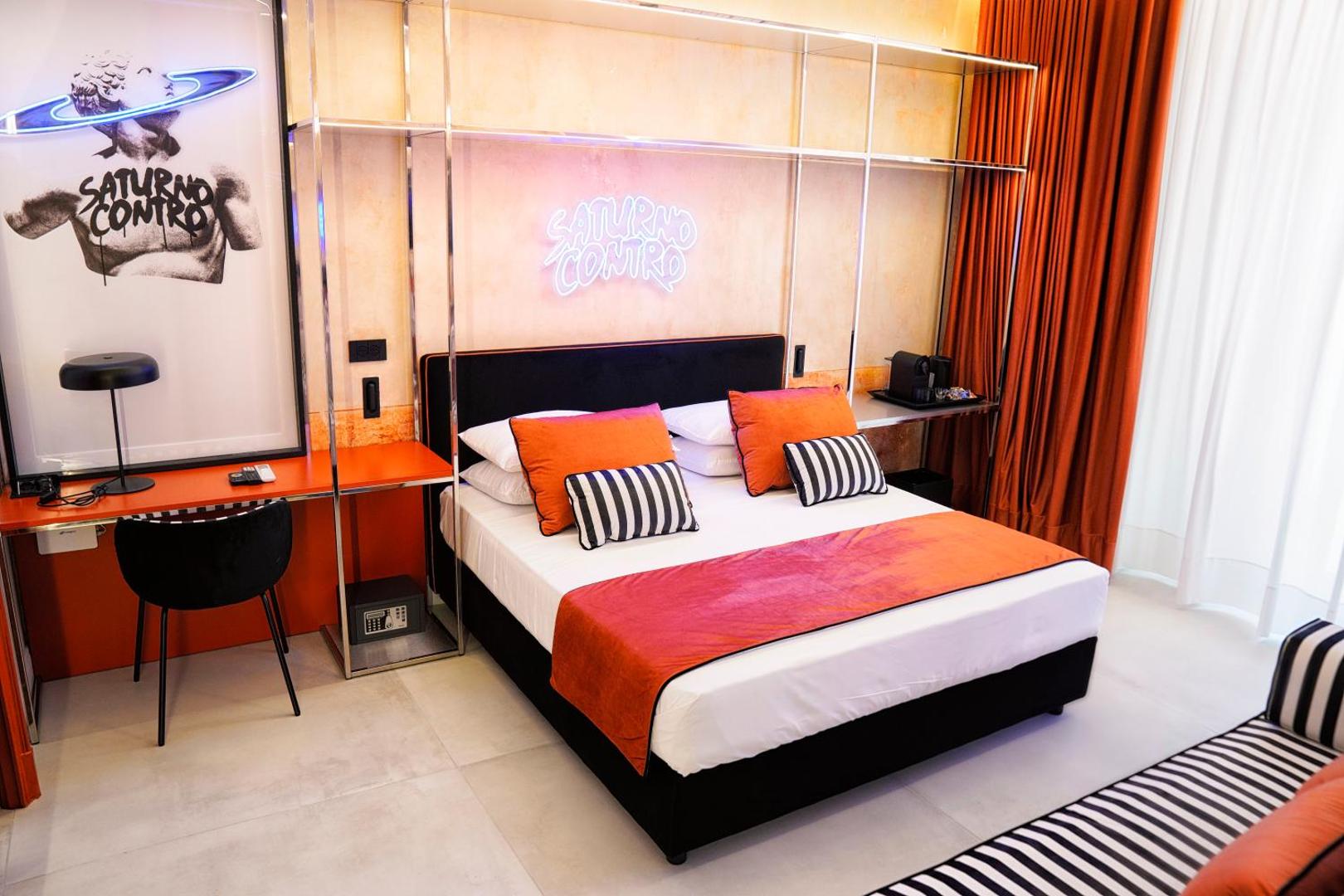 Suite Saturno Contro: camera con letto, insegna al neon e opera con statua e anello di Saturno
