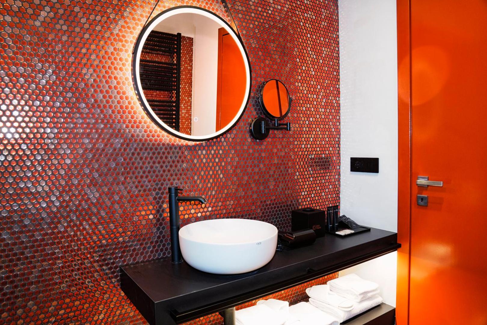 Lavabo con specchio tondo retroilluminato su mosaico a nido d'ape rosso