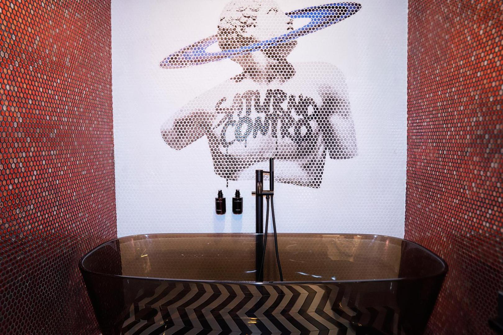 Vasca nera freestanding davanti al murale Saturno Contro in mosaico, pavimento a chevron