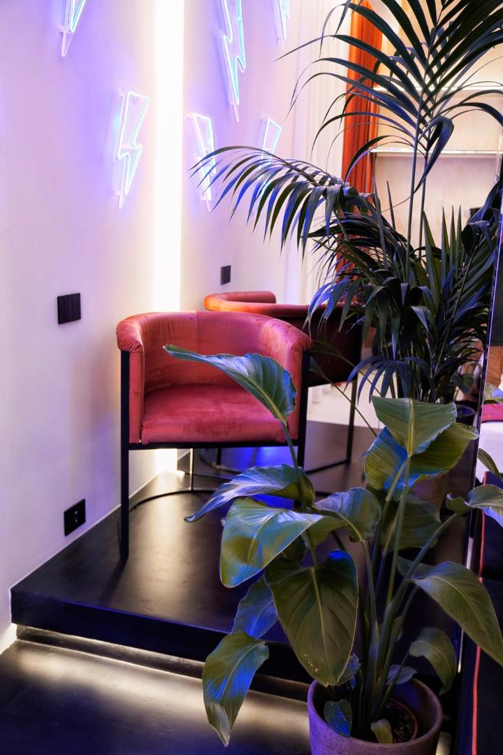 Angolo relax con poltrona in velluto e insegne al neon a fulmine