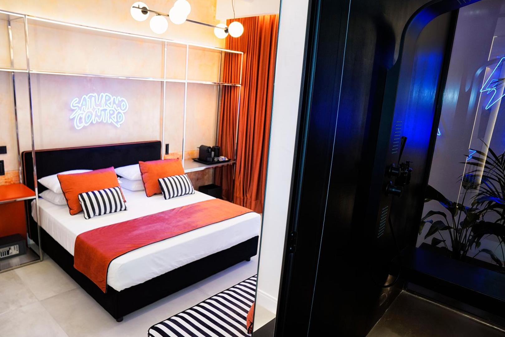 Camera con letto e insegna al neon Saturno Contro accanto alla doccia Hammam
