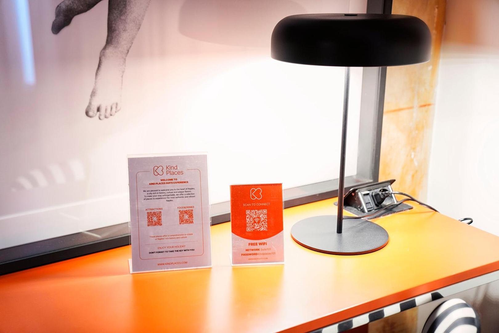 Postazione da lavoro con lampada, scheda di benvenuto Kind Places e QR del Wi-Fi gratuito