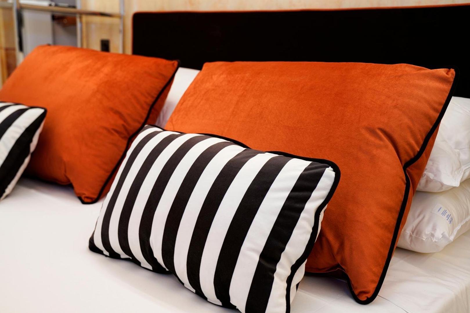 Dettaglio del letto con cuscini arancio e a righe bianche e nere