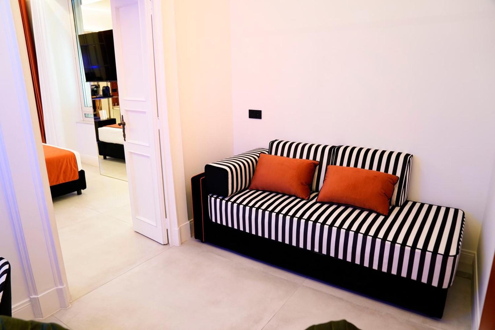 Divano letto a righe con cuscini arancio davanti alla parete a specchio